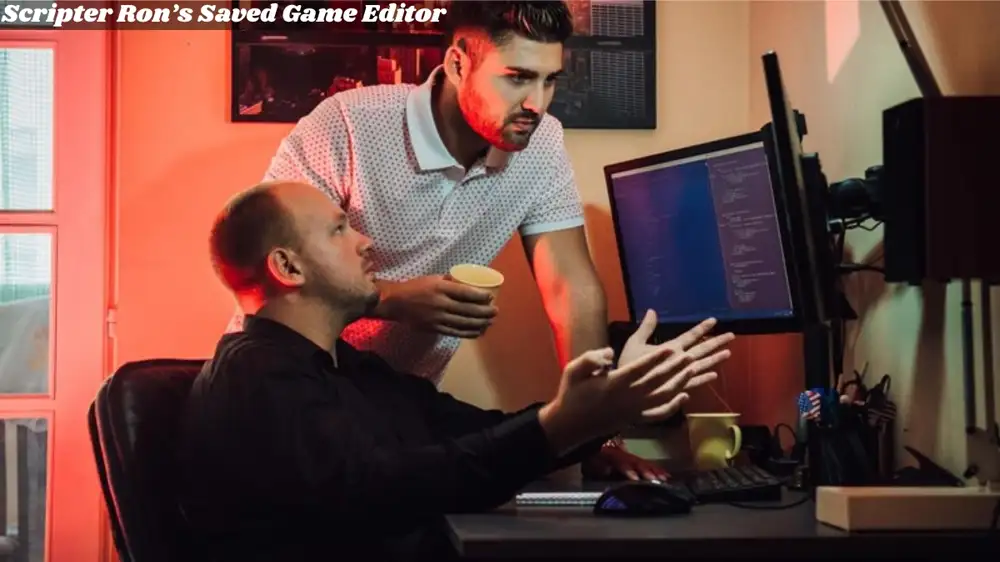 two men sitting at a desk with Game Editor a computer